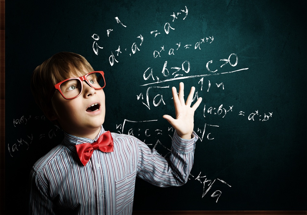 Genius boy in red glasses near blackboard with formulas.jpeg